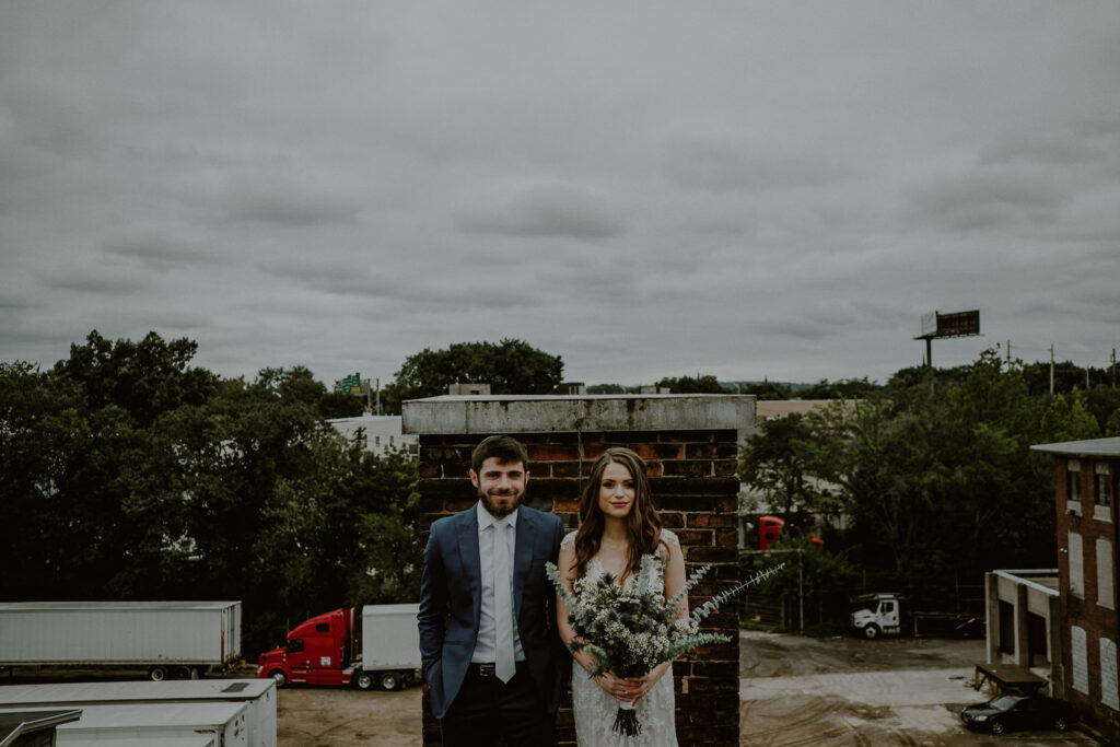 bride and groom looking straight at camera in urban industrial setting on rooftop