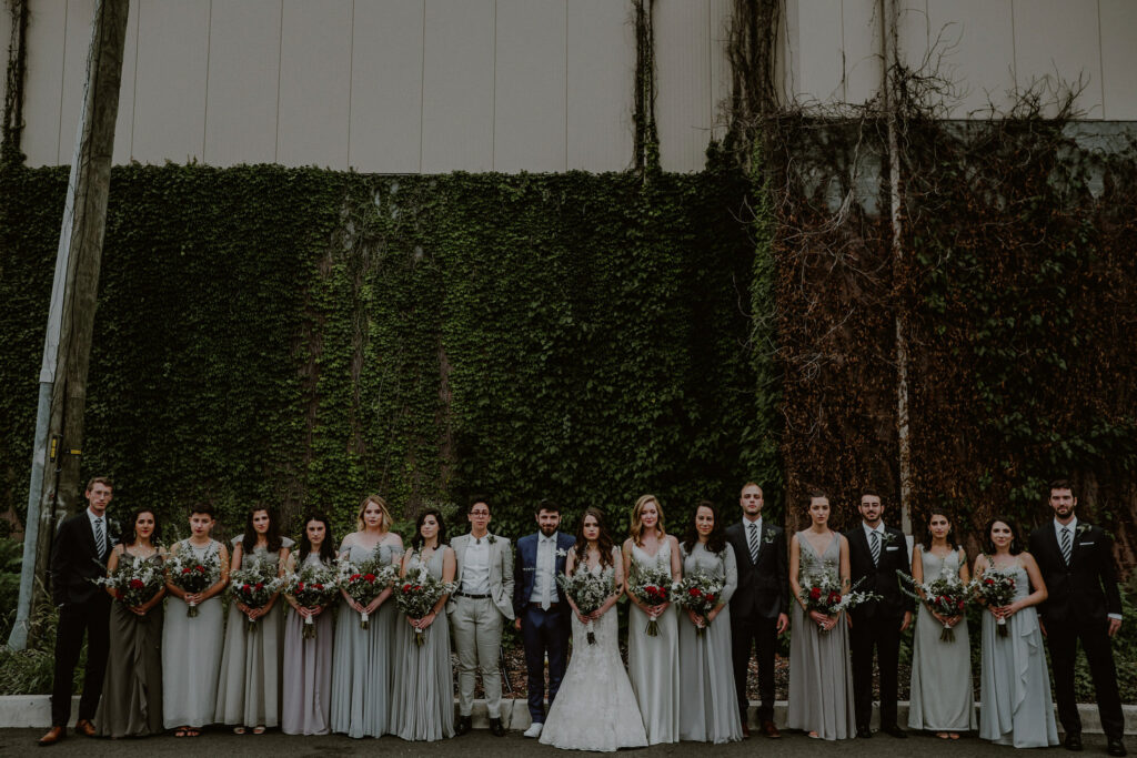 bridal party posed in front of vine wall 
