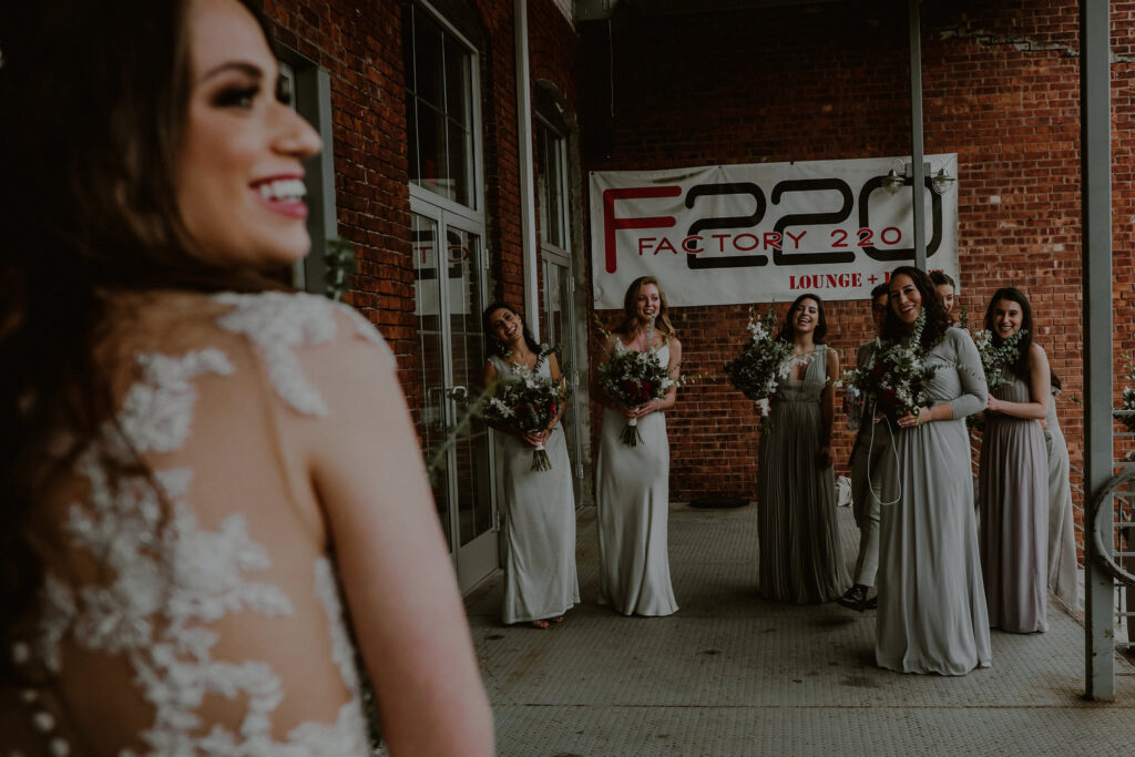 candid moment of bride and bridal party in front of factory 220 entrance sign