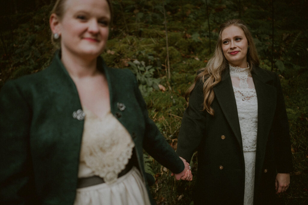 two brides holding hands in woods