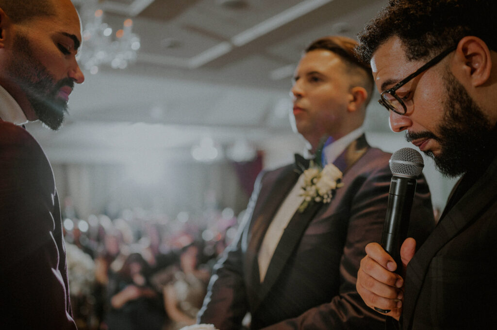 officiant standing in front of two grooms during wedding ceremony