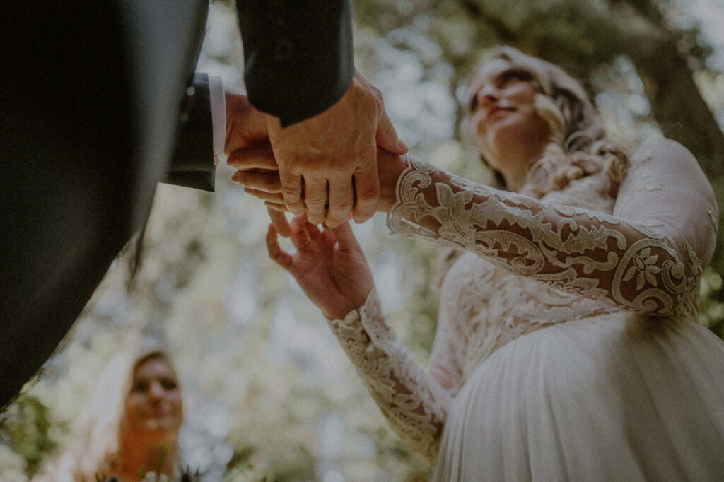 hands of bride and groom during vows and ring exchange