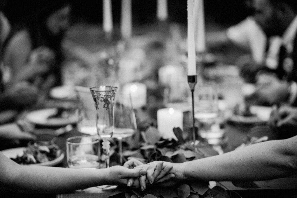 hands extended across dinner table of couple