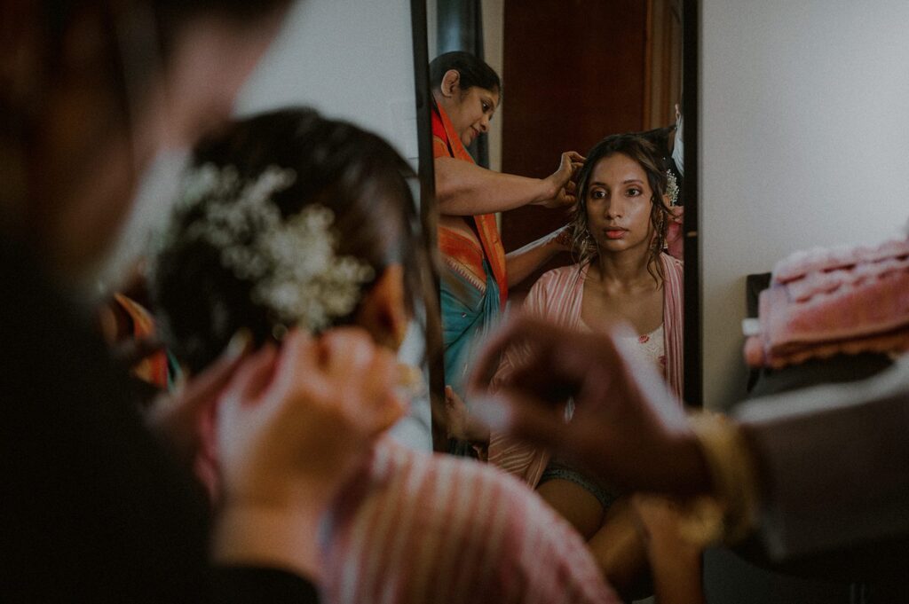 bride looking in mirror as hair is done for wedding