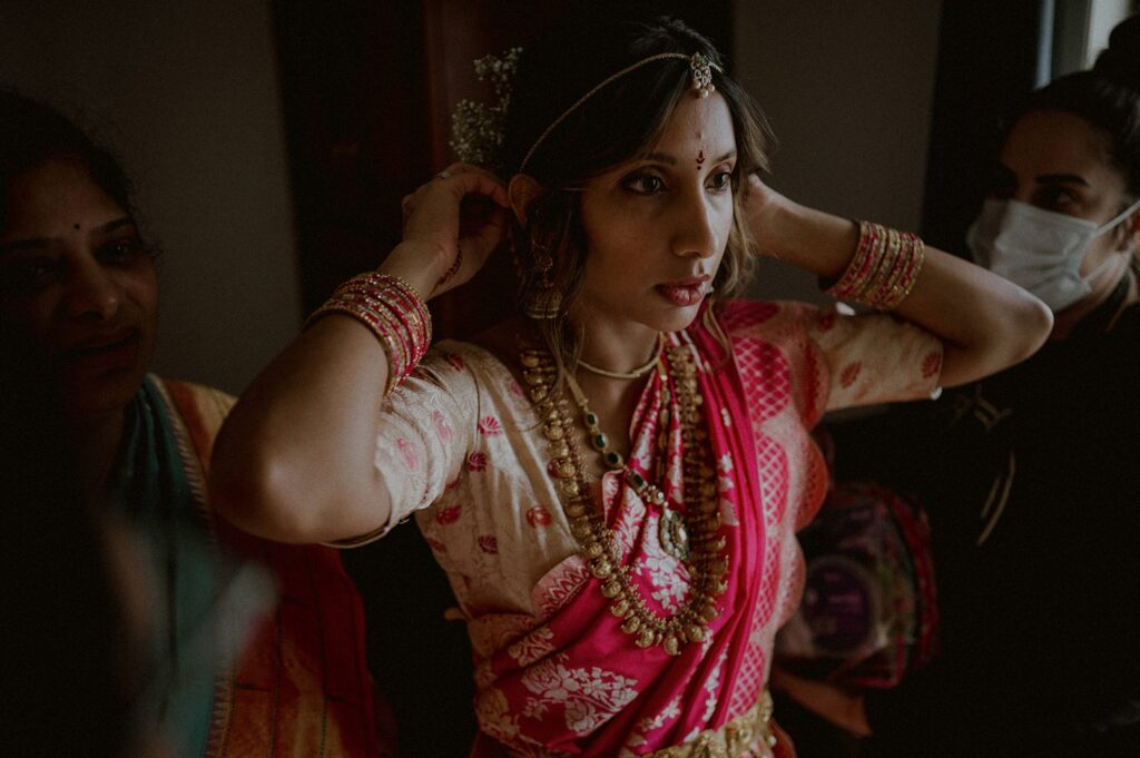 family members of bride in indian wedding attire help bride with hair piece