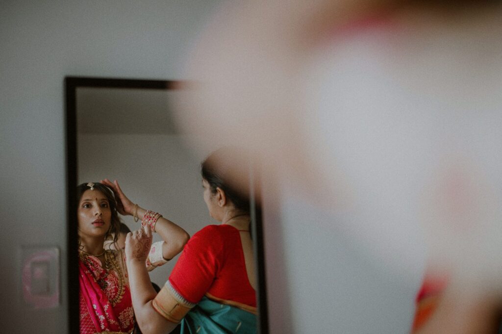 indian bride reflection in mirror as she secures head piece