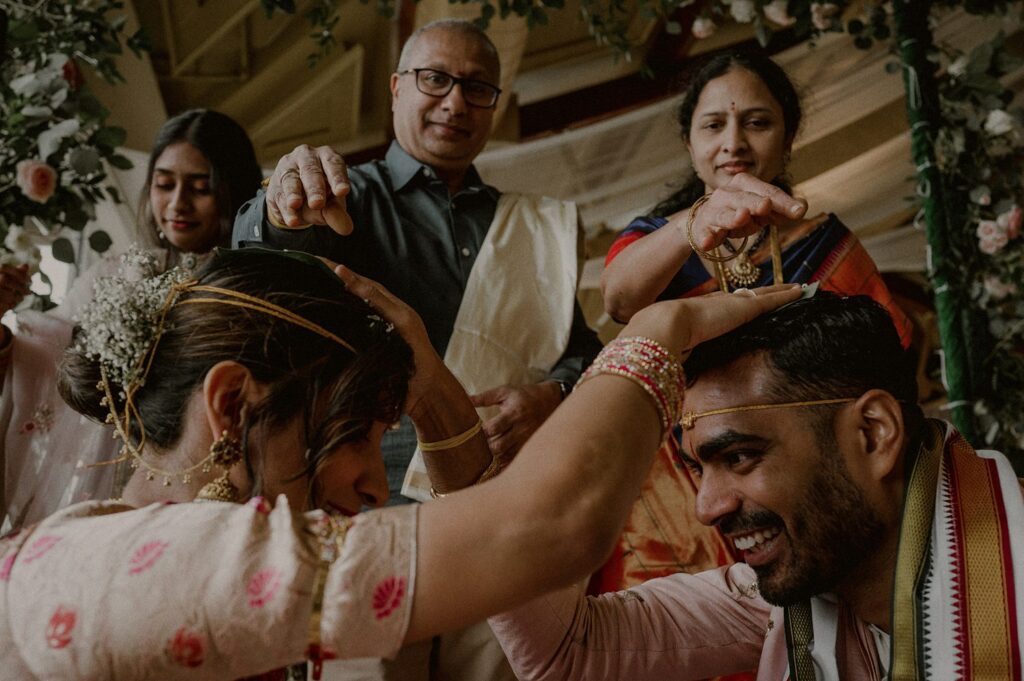 bride's parents bless bride and groom with rice grains as couple puts hands on each other and smiles