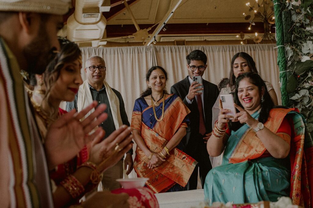 guests at indian wedding looking and laughing with bride and groom