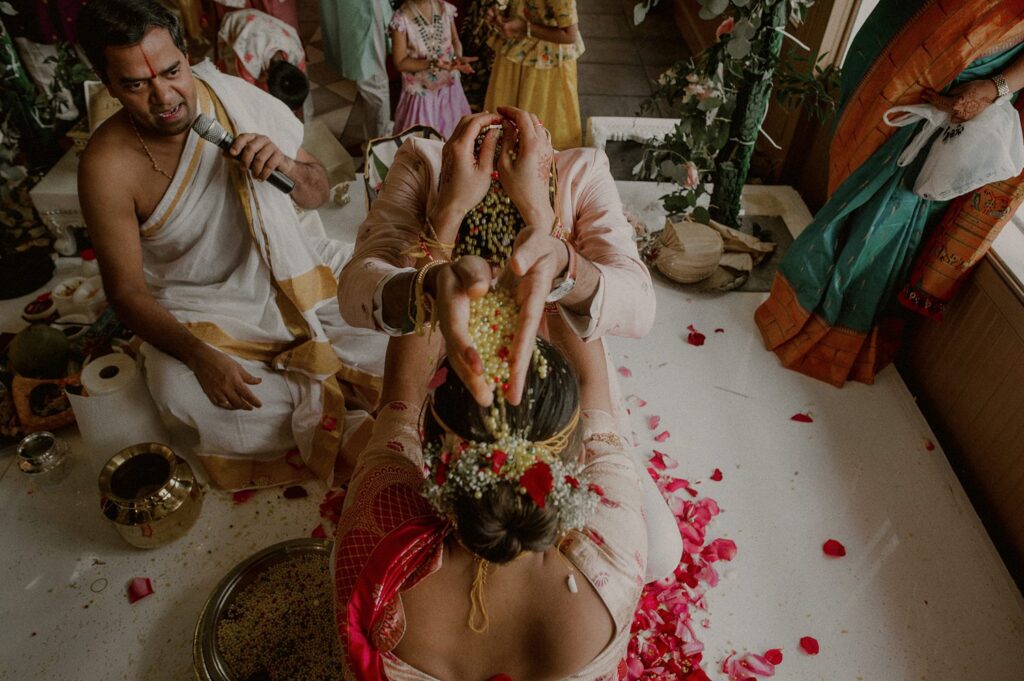 bride and groom pour beads on each other's heads in traditional south indian wedding ceremony on mandap