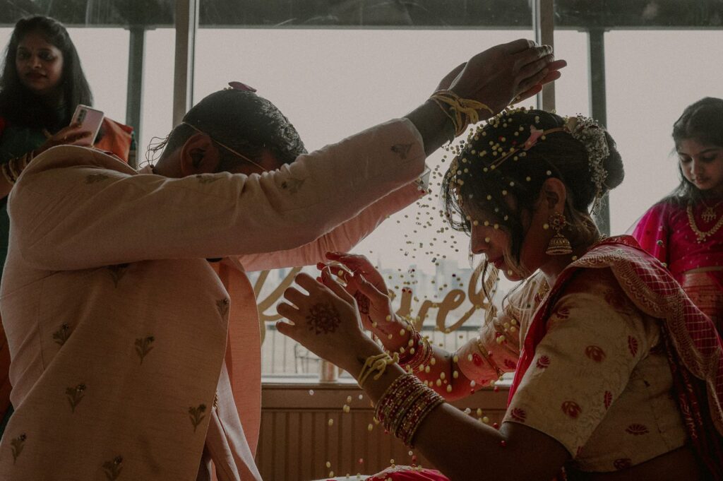 groom pours beads on bride's head in indian wedding ceremony