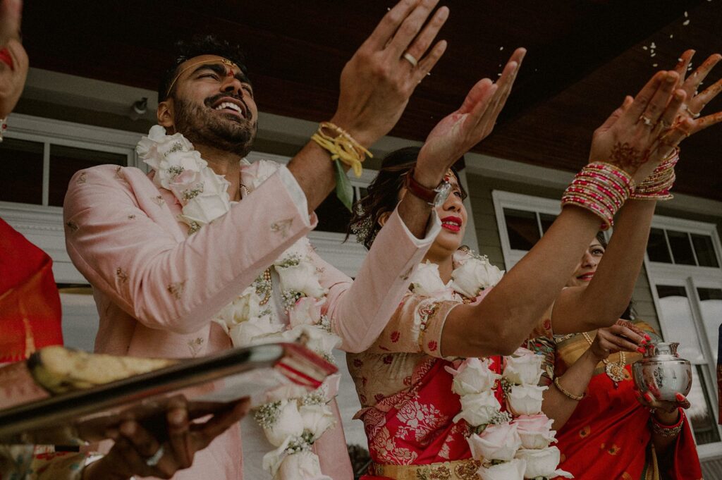 bride and groom point to the sky outdoors as part of indian wedding ritual