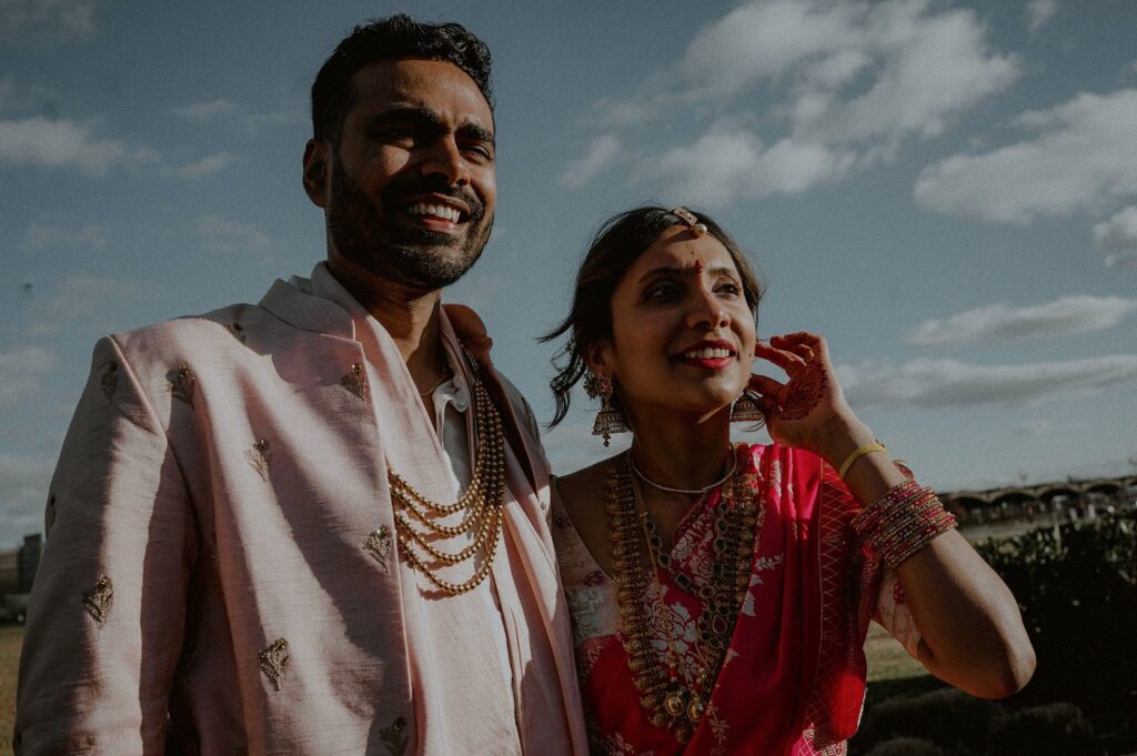 candid portrait outdoors of liberty house of indian bride and groom looking off to side