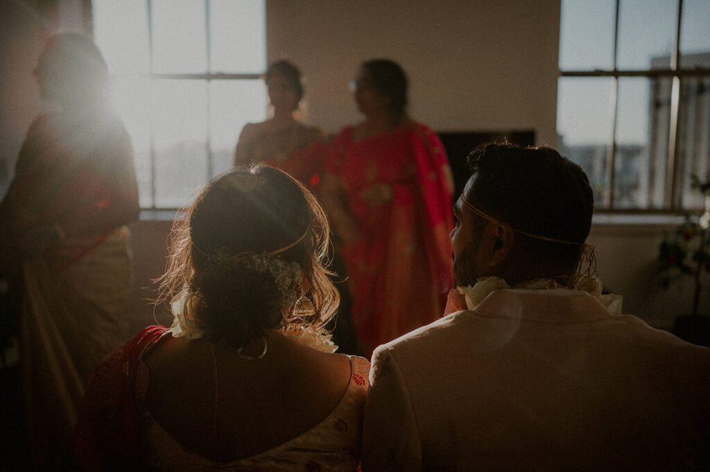 bride and groom sitting together with sun flaring in front of them