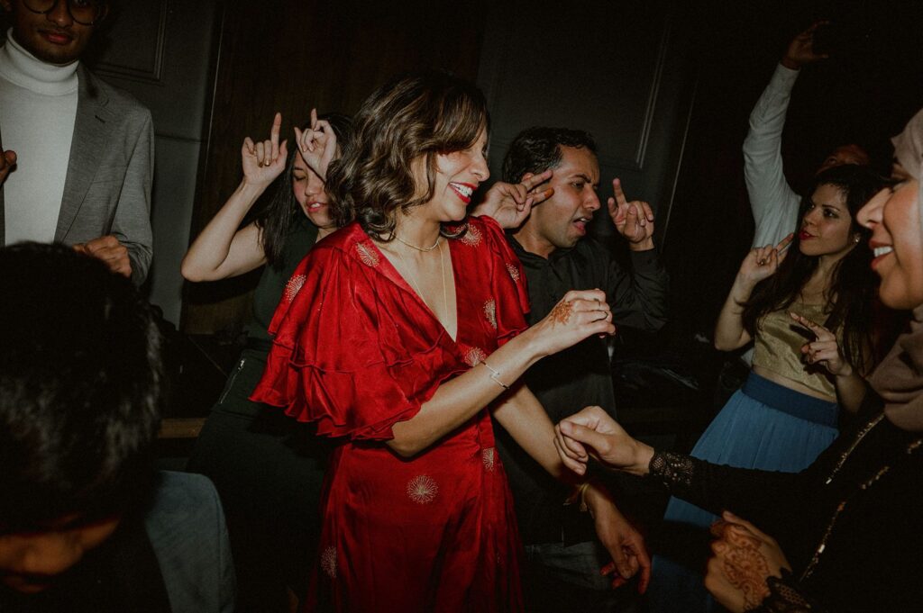 bride in red dress dances amongst guests at wedding reception