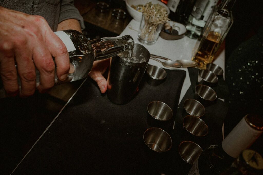 drink being poured into a shaker with ice