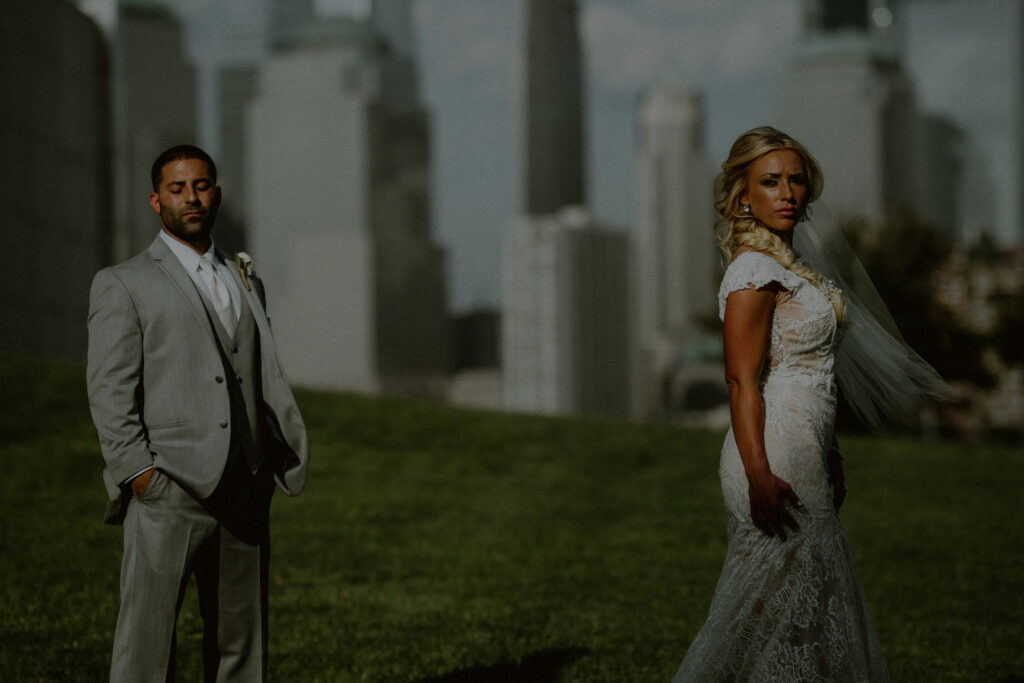 bride and groom in moody pose in front of nyc skyline at liberty state park