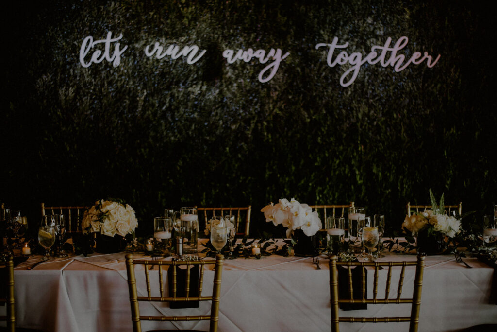 beautiful wedding tablescape with neon sign in front of a living wall 