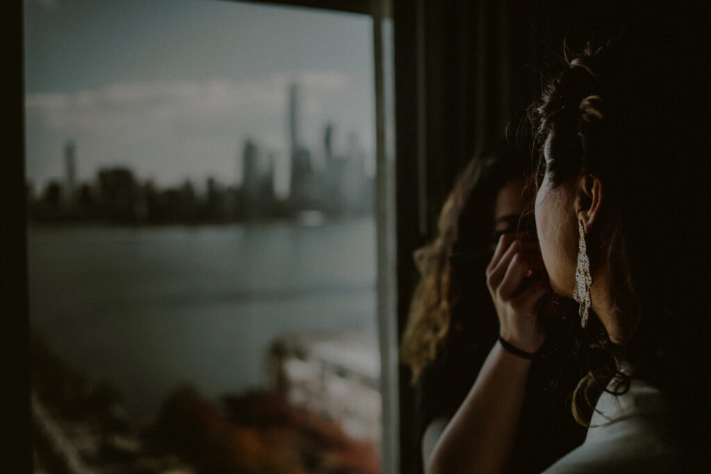 bride getting ready and putting on makeup in hotel suite with outdoor view of NYC skyline