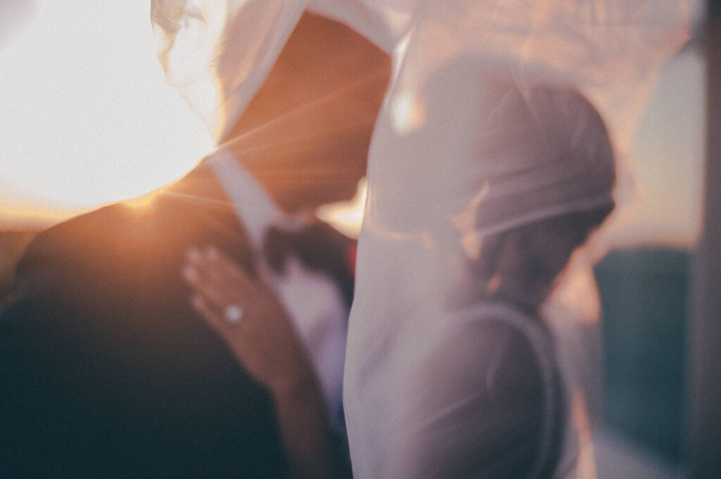 bride and groom creative photo kissing in front of sunset