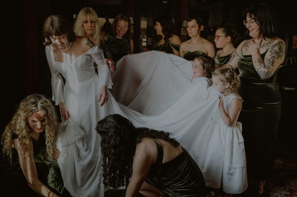 bride in wedding dress surrounded by bridal party as she gets dressed