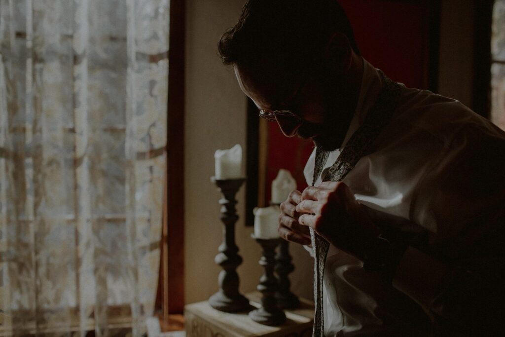 silhouette of groom as he puts on a tie