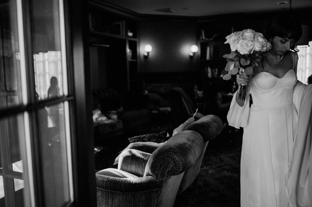 black and white photo of bride holding flowers and leaving bridal suite