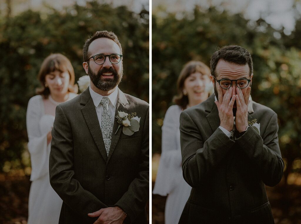 groom smiling and wiping off tears as he awaits bride standing behind him for first look