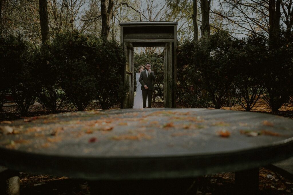 bride and groom first look from afar with radiant disc sculpture in foreground