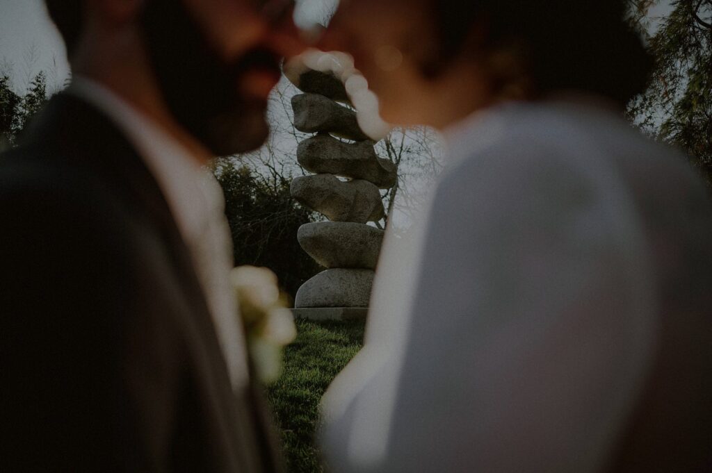 out of focus image of bride and groom's faces with sculpture in the background