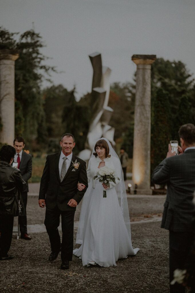 bride and father walking into outdoor ceremony space