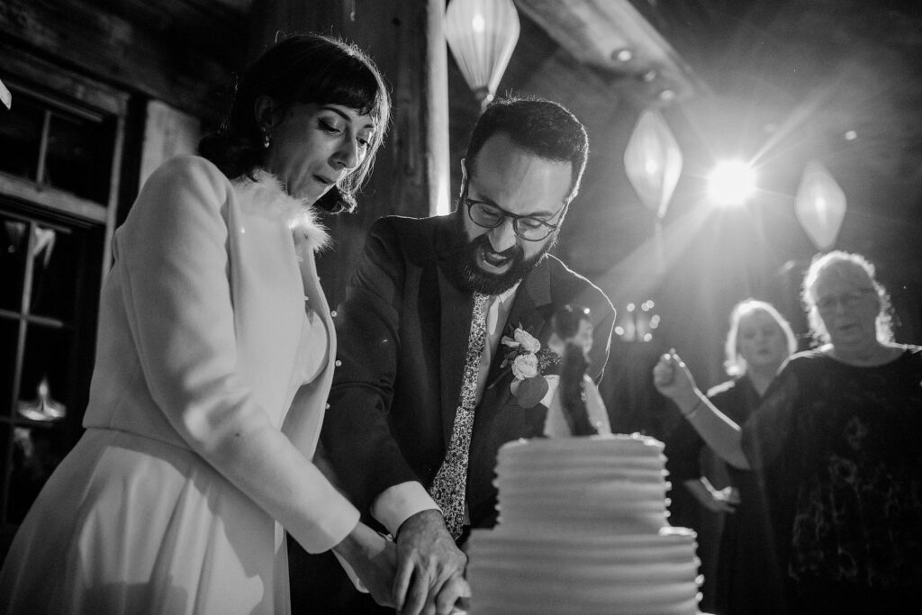 black and white photo of bride and groom cutting cake with funny expressions