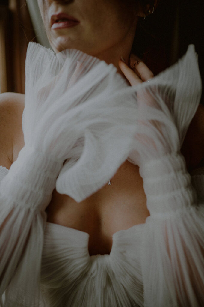 close up portrait of bride with puffy sleeved wedding dress and hands framing face