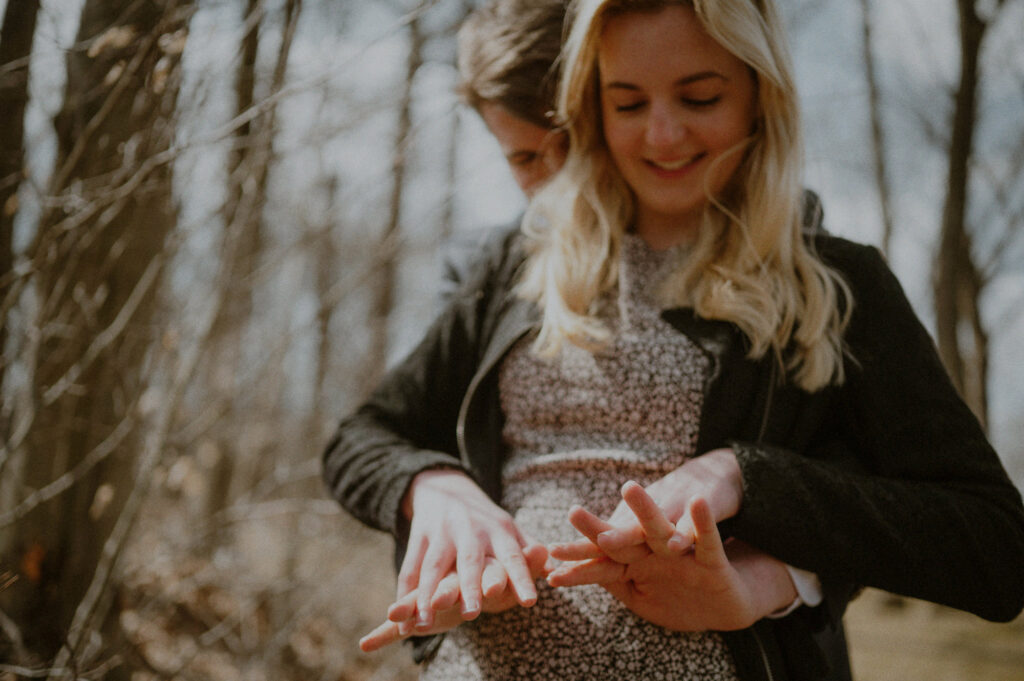 couple embracing and woman looking at engagement ring on finger