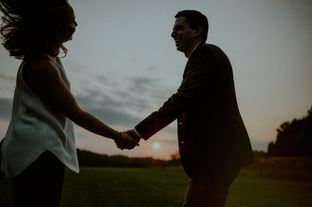 couple holding hands in front of sunset