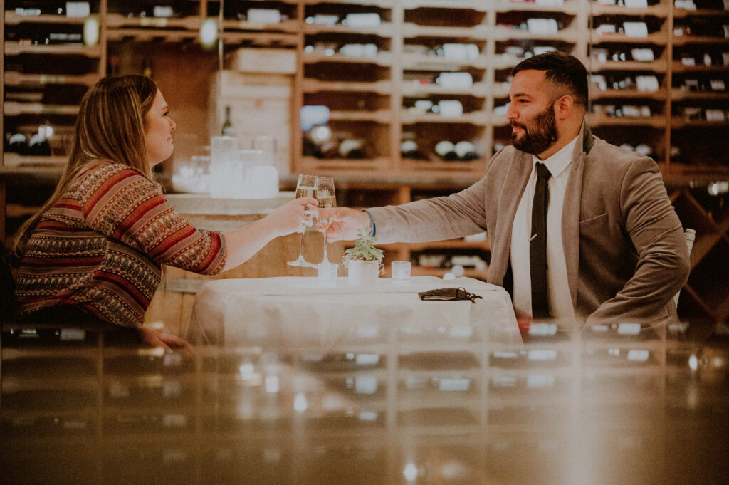 man and woman celebrating engagement with champagne at private wine cellar