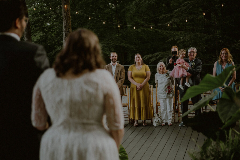 small crowd of family and friends looks on at bride and groom in intimate elopement ceremony