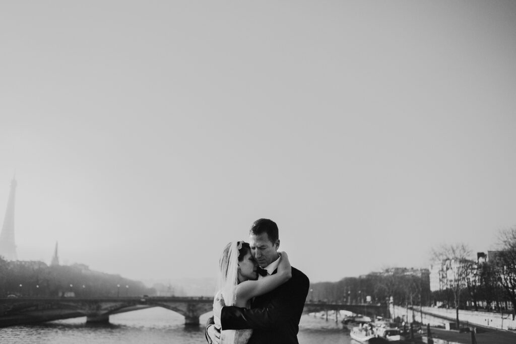black and white photo of couple embracing in front of the eiffel tower in paris
