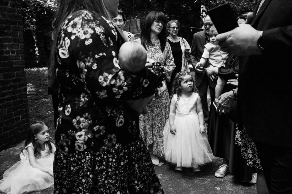documentary photo of children looking lost in the middle of large group family photo at wedding