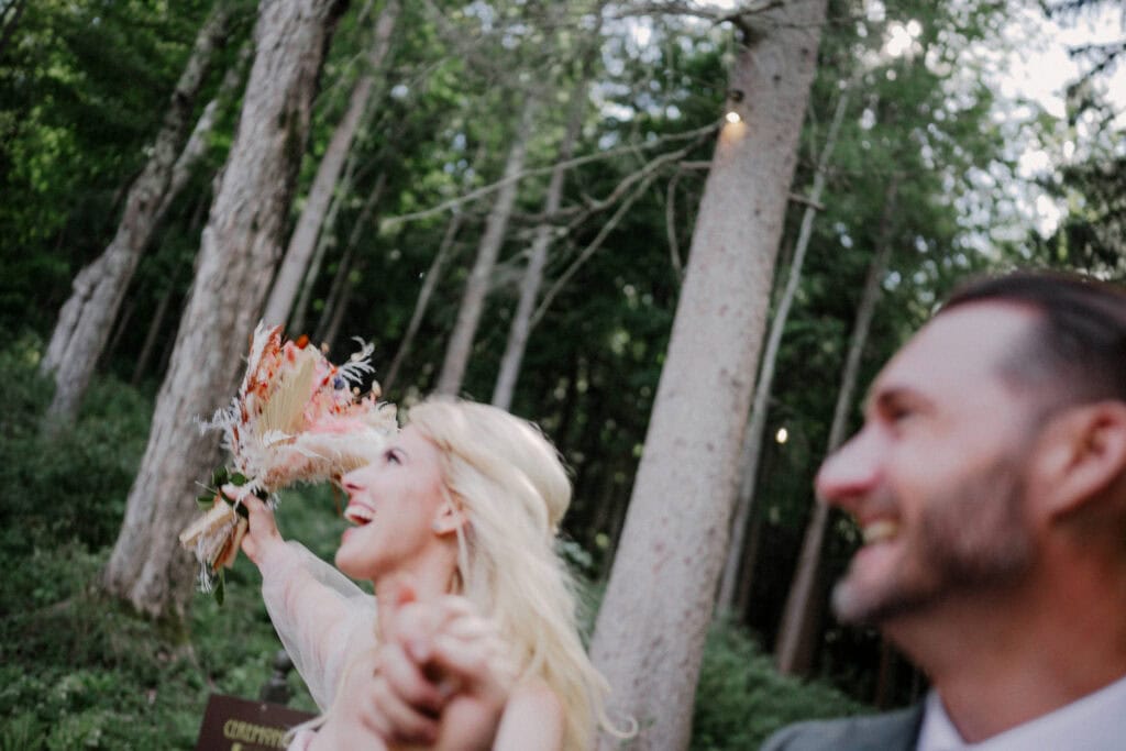 bride and groom ecstatic after leaving ceremony with hands in the air