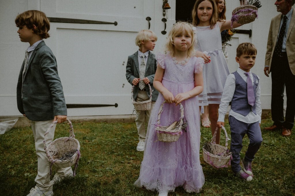 flower children and ring bearers about to enter wedding ceremony in outdoor backyard wedding