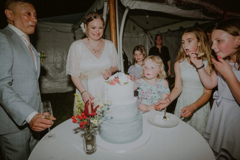 bride and groom surrounded by wedding cake and children and making funny expressions